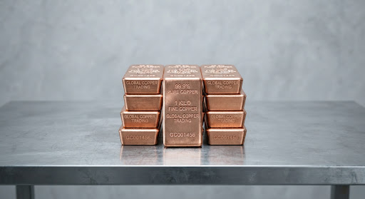 Stack of 99.9% pure copper bullion bars on an industrial steel table
